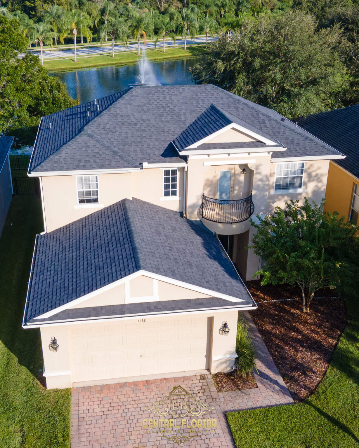 Aerial view of a residential home in Central Florida with a new gray shingle roof, landscaped yard, and driveway, emphasizing storm damage repair and roofing services by Central Florida Equity Builders.
